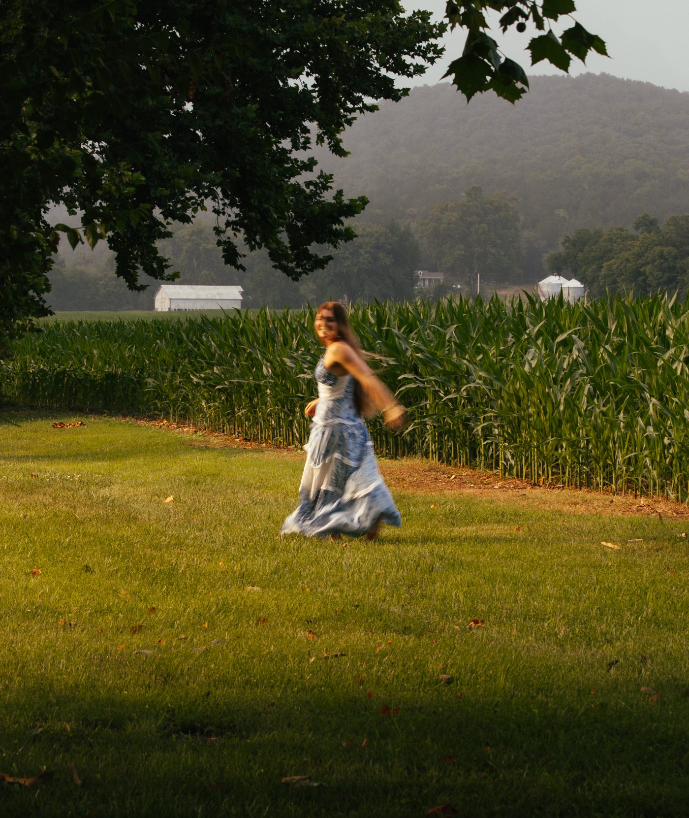 Candid portrait twirling in a floral dress at the edge of a cornfield