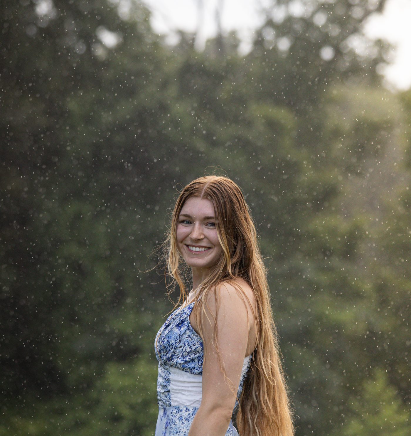 Smiling portrait in the rain, close up with raindrops falling