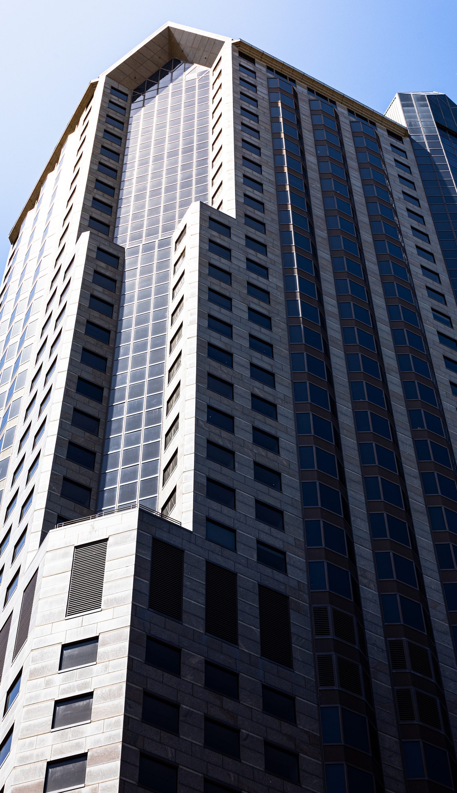 Tall modern glass and stone skyscraper corner at a dramatic upward angle